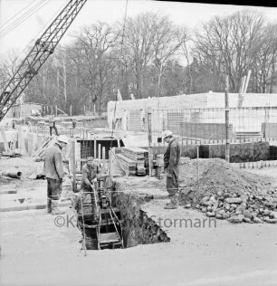 Rathaus und Bürgerhaus Glinde [später Marcellin-Verbe-Haus]: Bau: Blick auf Fundamente, Keller und Grundmauern: vorn drei Arbeiter an Schacht: darin Baggerschaufel