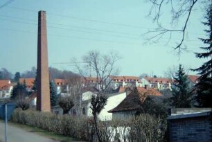 Ortsansicht; im Hintergrund neu gebautes Wohngebiet; hoher Schornstein