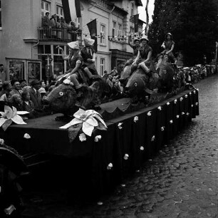 Karpfenfest: Umzug: Festwagen, Fischerinnen reiten auf Karpfen: dahinter am Straßenrand und auf Balkon Zuschauer, mit Regenschirmen, Hausfassaden mit Fahnenschmuck, Wimpelgirlanden, 8. Oktober 1961