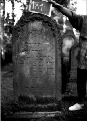 Grabstein 181 (Index: 100109705) Material: Sandstein Zustand: abgeblättert mit Textverlust Maße HxBxT: 134x50x23 cm Beschreibung: Stele, profilierter Sockel, Rundbogenabschluß, Schriftfeld eingetieft Symbolik: Rundbogenfries: Grabstein 181