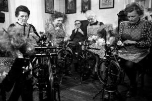 Frauen beim Flachsspinnen in Wohnstube