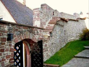 Dietlingen-Kirchhof im Nordwesten mit Torbogen sowie abgetreppter Kirchhofmauer mit erhaltenen Konsolsteinen und Steinbrüstung des Wehrgangs