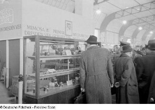 Besucher vor Vitrinen am Messestand des VEB Mimosa Dresden