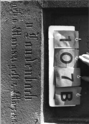 Grabstein 107 (Index: 100116419) Material: Sandstein Zustand: verwittert mit Textverlust Maße HxBxT: 175x57x20 cm Beschreibung: doppelt aufgesockelte Stele mit Rundbogenabschluß und eingetieftem Schriftfeld, weiteres Schriftfeld am oberen Sockel: Grabstein 107B