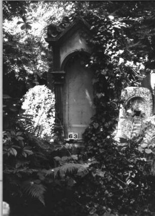 Grabstein 63 (Index: 100084986) Maße HxBxT: 210x65x37 cm Beschreibung: Ädikula m. Säulen, giebelart. Abschl. m. Verdach. , Schrift eingetieft m. Rundbog. abschl: Grabstein 63