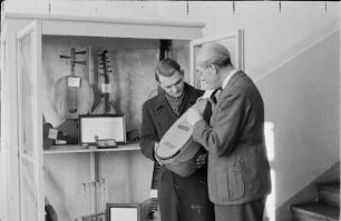 Markneukirchner Cocktail : Musikinstrumenten-Museum Markneukirchen. Zwei Männer mit Mandoline vor Ausstellungsschrank mit Zupfinstrumenten