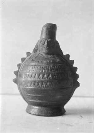 Tongefäß mit Kopf am Henkel und geometrischem Relief