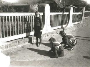 Kinder beim Murmelspiel auf einer Dorfstraße