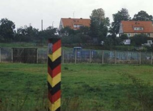 Deutsch-deutsche Grenze : Ein Grenzpfahl vor der deutsch-deutschen Grenze bei Ellrich. Im Hintergrund Wohnhäuser von Ellrich (DDR).