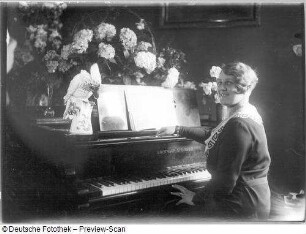 Elisabeth Rethberg mit Blumenarrangement und Geschenken : Porträt Elisabeth Rethberg aus feierlichem Anlaß mit Blumenarrangement und Geschenken in ihrer Wohnung. Fotografie von Ursula Richter, um 1928