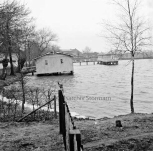 Gräberkate: Mühlenteich: links Bootshaus: dahinter Steg mit Pavillons: vorn Zaun und Baum