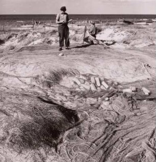 Fischer bei Netzreparaturen am Dünenstrand, um 1960