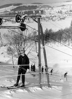 Deutschland. Skigebiet um Sankt Andreasberg im Harz. Eine Skifahrerin lässt sich im Schlepplift den Hang hinauf befördern. Im Hintergrund befindet sich der gleichnamige Ort.