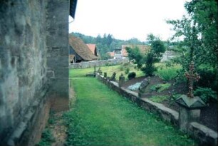 Weg vom Tor des Kirchhofes zur Eingangstür der Kirche, auf einer Mauer eine Reihe alter Grabsteine
