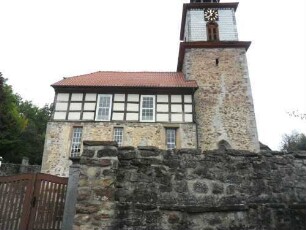 Evangelische Kirche - Kirchturm und Langhaus (frühgotisch-mit Fachwerkaufsatz 19 Jhd) von Süden über Kirchhofmauer (erhaltene Konsolsteine der Wehrgangsbrüstung mit neuer Aufmauerung)