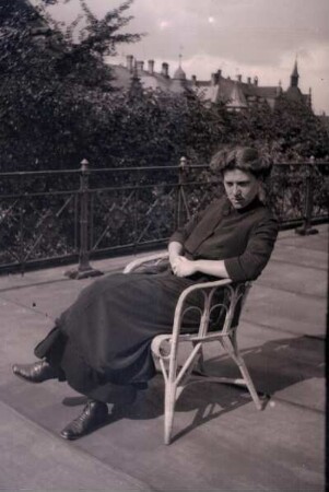 Frau, auf einem Armlehnstuhl im Freien sitzend