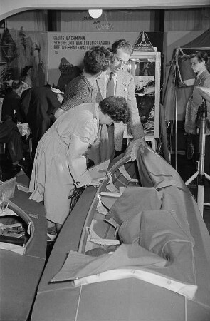 Mehrere Personen begutachten auf der Leipziger Herbstmesse 1955 ein Kanu