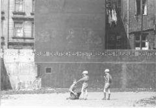 Spielende Jungen an Mauer