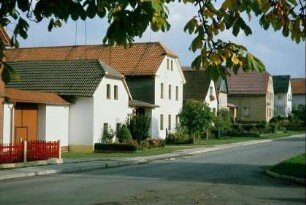 Dorfstraße mit giebelständigen Häusern und Vorgärten