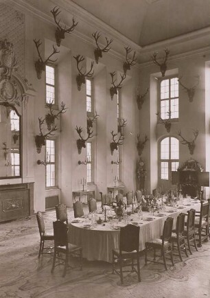 Moritzburg, Großer Speisesaal (auch Geweihsaal genannt) mit gedeckter Tafel (polnisches Krönungsservice und Tafelaufsatz Augusts des Starken). Übereckansicht, Hochaufnahme.