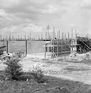 Volksschule Wiesenfeld: Holstenkamp: Neubau: Grundmauern mit Gerüsten: davor Baumaterial: vorn links Büsche