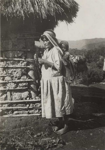 Femme Arhuaco avec enfant et petit cochon en train de fabriquer un cabas