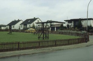 Wohngebiet mit Einfamilienhäusern, davor Spielplatz
