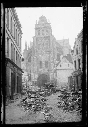 Saint-Quentin (Dep. Aisne, Frankreich): Westportal der "zerstörte[n] Kathedrale", im Vordergrund Schutthaufen auf einer Straße (Distanzaufnahme)