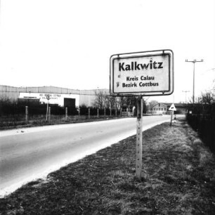 Saßleben-Kalkwitz (Kreis Calau). Hallen des ehemaligen VEG Obstbau Cottbus, Kühllager Kalkwitz. Ansicht mit Ortseingangsschild (gemäß StVO DDR)