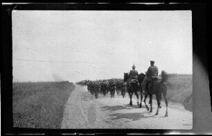 Nicht identifizierbare Gegend in Nordfrankreich oder Belgien: Soldaten mit Pickelhaube, dahinter 2 Reiter, auf einer unbefestigten Landstraße (Rückansicht, Distanzaufnahme)