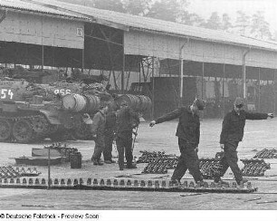 Goldberg (Kreis Lübz). Nationale Volksarmee - Landstreitkräfte. Panzerregiment 8 (PR-8). Freifläche vor Panzerhallen. Soldaten bei Instandsetzungs- bzw. Wartungsarbeiten an Gleisketten für Kampfpanzer T-54