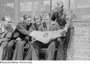 Arbeiter während des Lesens der Leipziger Volkszeitung