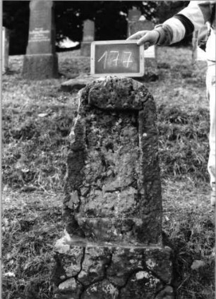 Grabstein 177 (Index: 100090502) Material: Kalkstein Zustand: beschädigt/Schriftplatte fehlt Maße HxBxT: 110x38x28 cm Beschreibung: Stele, Sockel rustica, Segmentbogenabschluß, rechteckiges Schriftfeld eingetieft: Grabstein 177