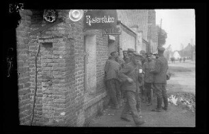 Nicht identifizierbare Ortschaft in der Gegend von Cambrai (Dep. Nord, Frankreich), Bourlon (Dep. Pas-de-Calais, Frankreich) und Esnes (Dep. Nord, Frankreich): Soldaten vor einem niedrigen Backsteingebäude mit dem Ausleger "Rasierstube"