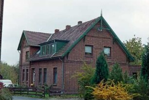 Fritz-Berodt-Straße: traufständiges Wohnhaus aus Backstein: Straßenfront mit Eingangstür, links Quergiebel: Giebelseite mit Giebelzier, Giebelpfahl: rechts flacher Anbau: Vorgarten, Holzzaun