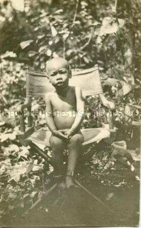 Porträt eines afrikanischen Kindes auf einem Klappstuhl