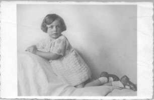 Genja Huebner, geb. Berger, im Häkelkleid, halbaufgerichtet auf einem Bett