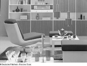 Drehstuhl : Möbelprogramm "variopur" (1973; VEB Petrolchemisches Kombinat Schwedt). Drehstuhl und zwei Hocker mit Beistelltisch (1973; VEB Petrolchemisches Kombinat Schwedt) vor Anbauwand