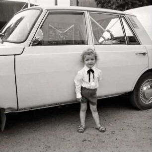 Fotografie eines Jungen vor einem Auto