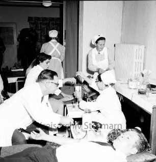 Deutsches Rotes Kreuz DRK: Volksschule: am Schweinemarkt: erste Blutentnahmeaktion der Zentrale des DRK-Blutspendedienstes Nord Lütjensee: Spender, Spenderin auf Liegen: DRK-Krankenschwestern, DRK-Helferinnen, Chefarzt des Blutspendedienstes Schuberth