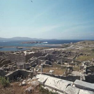 Delos. Blick von der Mauerkrone des Theaters auf Römerviertel und Agorá. Drüben Rhíneia. 74