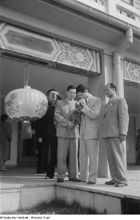 Mehrere Personen, darunter eine Fotografierende, unter den Kolonnaden des chinesischen Pavillons der Leipziger Herbstmesse 1954