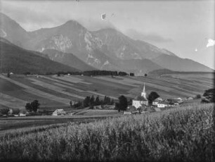 Dorf im Tal : Ein Dorf von Feldern umgeben in einem Tal. Im Hintergrund hohe Berge