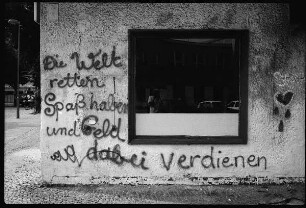 Fassade mit Inschrift "Die Welt retten / Spaß haben und Geld dabei verdienen"