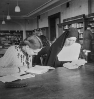 Berlin-Dahlem. Freie Universität Berlin, Boltzmannstraße 3. Nonne und Studentin im Lesesaal im Germanischen Seminar