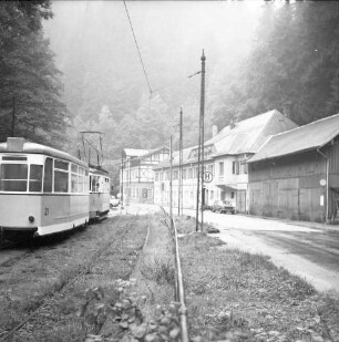 Sebnitz-Lichtenhain, Kirnitzschtalstraße. Endpunkt "Lichtenhainer Wasserfall" der Überlandstraßenbahn Bad Schandau - Lichtenhain. Ansicht mit Straßenbahnzug mit Hänger (Spurweite 1000 mm) in Fahrtrichtung Bad Schandau. Blick gegen Gaststätte und Pension "Lichtenhainer Wasserfall" (Nr. 11; 1852/1853)