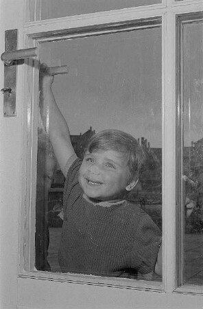 Ein kleiner Junge an einer Glastür einer Betreuungseinrichtung