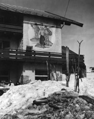 Bad Hindelang-Oberjoch. Hotel. Teilansicht der Fassade mit Wandbild "Bauern auf dem Weg zum Feld"