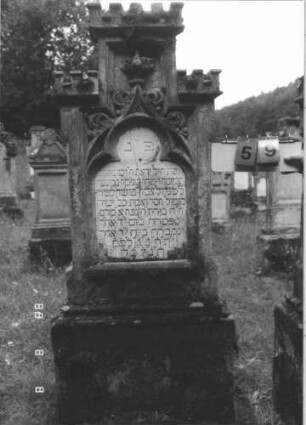 Grabstein 59 (Index: 99799525) Material: Sandstein, Schriftplatte Marmor Zustand: verwittert, Schriftplatte zerbrochen Maße HxBxT: 171x65x25 cm Beschreibung: Stele, Mittelerhöhung, Abdeckplatte, Zinnenaufsätze, Schriftplatte eingelassen mit Kleeblattabschluß, Sockel Symbolik: floral Besonderheit: vermutlich die Gattin von Marx Bloch, Vorsteher, Grabsteinnummer 58: Grabstein 59