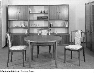 Wohnzimmermöbel. Eßtisch mit drei Stühlen vor einer Anbauwand